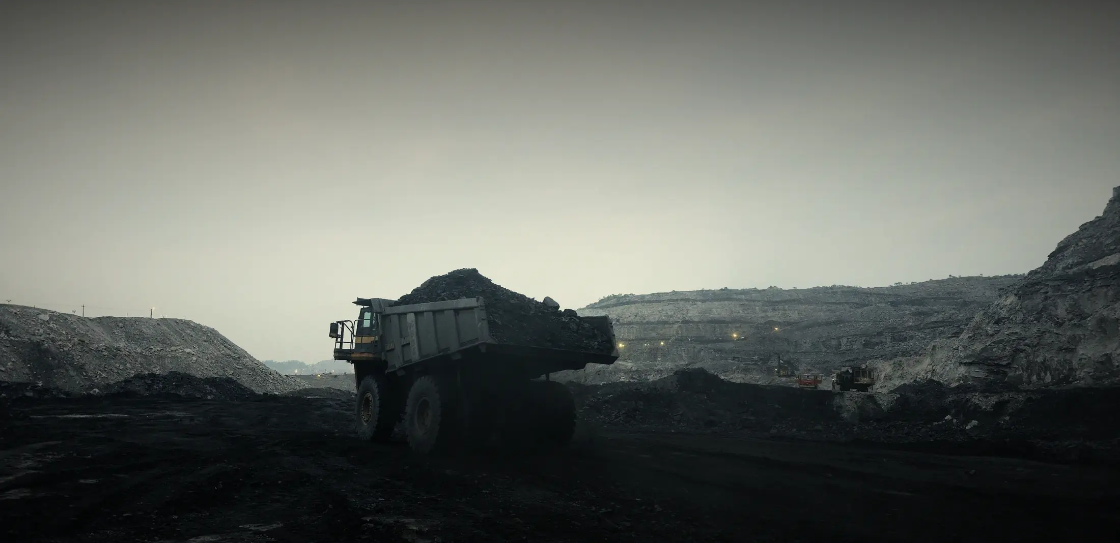 Loaded haul truck crossing an open-pit coal mine at dusk